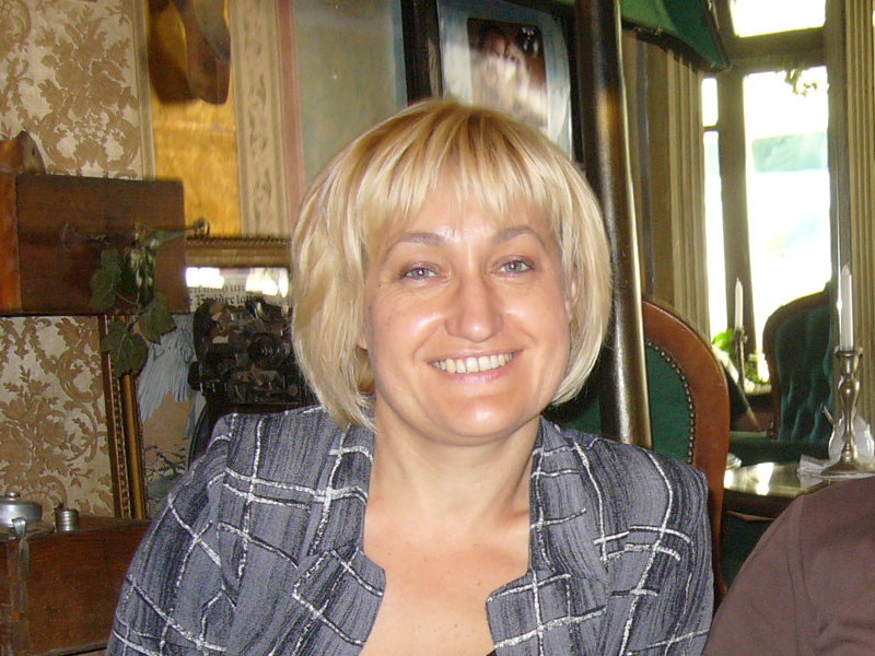Portret uśmiechniętej kobiety o blond włosach w szarym żakiecie, dyrektorki Biblioteki Politechniki Białostockiej Joanny Putko.