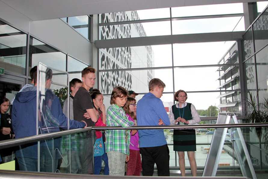 Grupa młodzieży w budynku ze szklaną ścianą w tle.