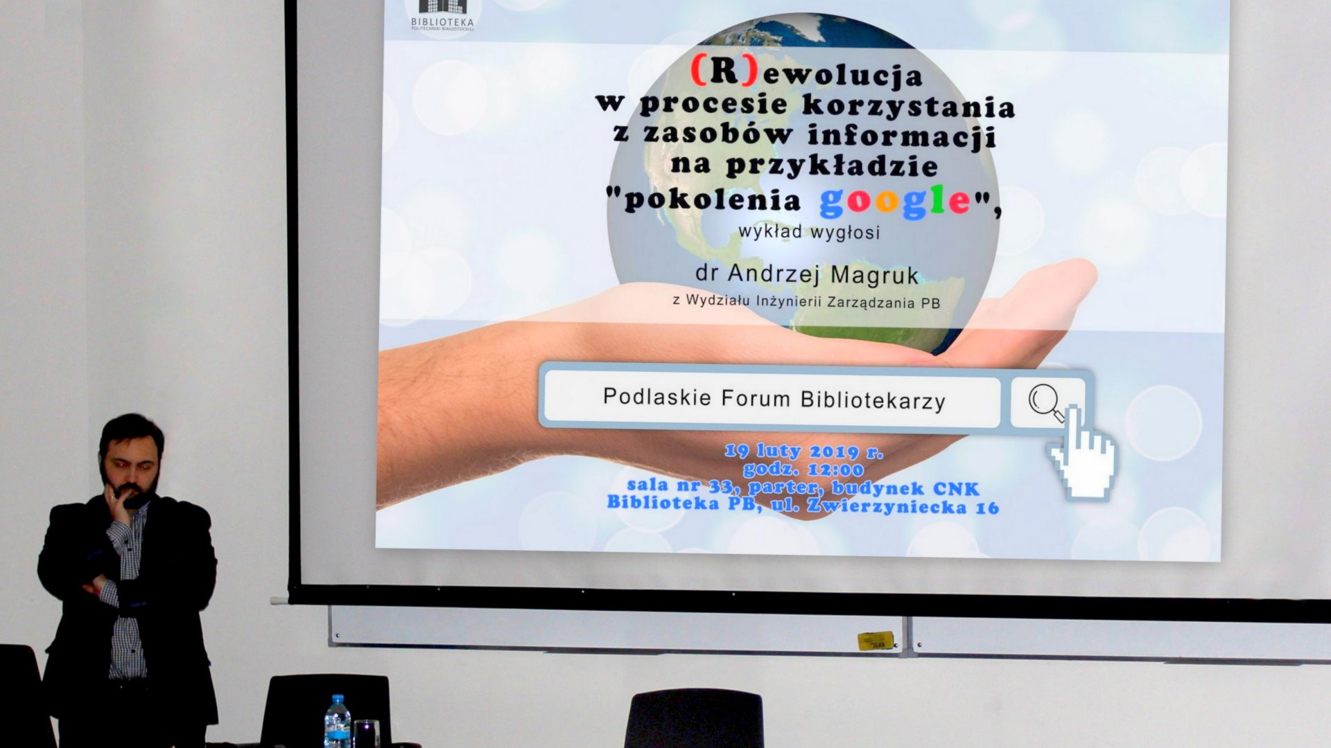 Mężczyzna w czarnej marynarce stoi przy ekranie projekcyjnym. Na slajdzie logo Biblioteki Politechniki Białostockiej, tytuł i autor prezentacji oraz data, godzina i miejsce spotkania.