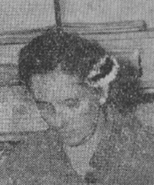Kobieta w średnim wieku o ciemnych włosach z lekko pochyloną w dół głową. Zdjęcie czarno-białe.
