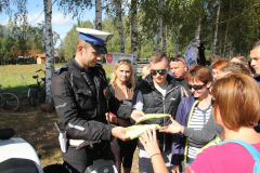 Policjant rozdaje koszulki odblaskowe uczestnikom rajdu.