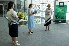 Z prawej strony odchodząca na emeryturę dyrektor biblioteki Maria Czyżewska, z lewej nowa dyrektor Elżbieta Kierejczuk z kwiatami, pośrodku wicedyrektor Anna Gogiel-Kuźmicka, czytająca z książki.