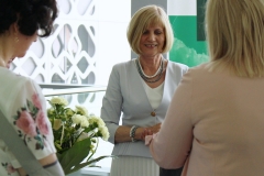 Na środku uśmiechnięta dyrektor biblioteki Maria Czyżewska. Przed nią stoją dwie kobiety. Jedna z nich trzyma bukiet białych kwiatów.