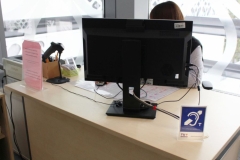 Stanowisko bibliotekarza w Czytelni Książek Biblioteki Politechniki Białostockiej wyposażone w pętlę induktofoniczną, ułatwiającą obsługę osób słabosłyszących. Na biurku widoczny jest komputer, czytnik kodów i oznaczenie informujące o dostępności urządzenia.