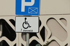 Znak drogowy z kopertą ze wskazaniem wyznaczonych 7 miejsc parkingowych dla osób z niepełnosprawnościami.