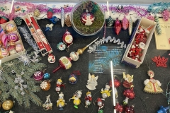 Gablota wystawowa z ozdobami świątecznymi z okresu PRL: grzybki, wata, pajacyki, szklane szyszki, muchomorki, kolorowe sople, bombki-reflektory, mikołaje.