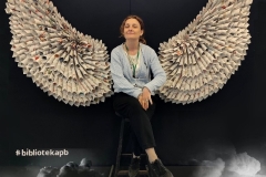 Zdjęcie wykonane na tle fotościanki, której motywem przewodnim są skrzydła anioła.