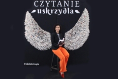 Zdjęcie wykonane na tle fotościanki, której motywem przewodnim są skrzydła anioła.