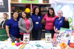 Grupa osób przy stoisku biblioteki; na stole ulotki, komiksy i gra