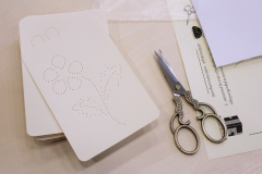 Kartonik z perforowanym wzorem kwiatu i ozdobne nożyczki na stole