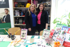 Dwie kobiety przed regałami reprezentują stoisko uniwersyteckiej biblioteki