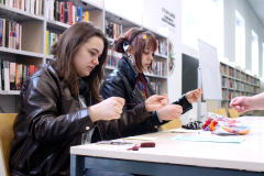 Dwie osoby przy stole wyszywają kartki