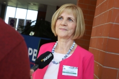 Uśmiechnięta Dyrektor Biblioteki Politechniki Białostockiej Maria Czyżewska stoi na tle ściany z czerwonej cegły i udziela wywiadu.