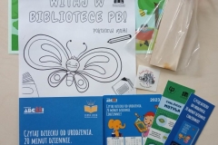 Materiały promocyjne leżące na drewnianycm stole.