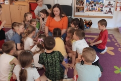 Siedzące na dywanie przedszkolaki z Przedszkola Samorządowego nr 43 i Pani, czytająca im  książkę.