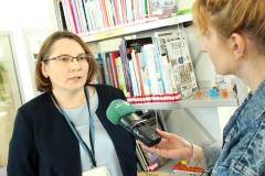 Zastępca dyrektora Biblioteki PB udziela wywiadu dziennikarzowi Radia Akadera. W tle regał z książkami.