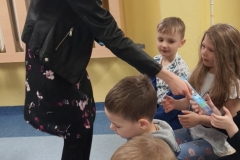 Młoda dziewczyna rozdaje dzieciom zakładki do książki.