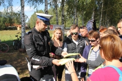 Policjant rozdaje koszulki odblaskowe uczestnikom rajdu.