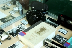 Fragment gabloty, w której widać aparaty fotograficzne Praktica, Concord, Fujika, stare czarno-białe zdjęcia oraz książkę o białostockich fotografach.