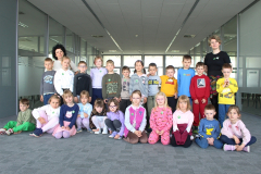Grupa uczestników pozuje do wspólnego zdjęcia w przestrzeni bibliotecznej