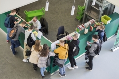 Grupa studentów stojąca przy zielonej ladzie w wypożyczalni